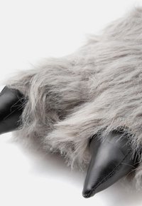 Grijs nepbont product met zwarte synthetische leren accenten, met spitse uiteinden die lijken op dierenklauwen. Zachte textuur en pluffy uiterlijk.