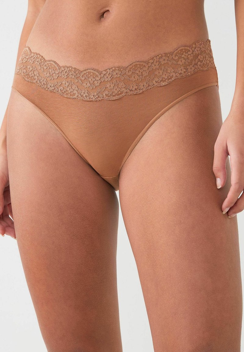 Tan slip met een kanten tailleband, voorzien van een gladde stof en een minimalistisch ontwerp. Het kant heeft een gegolfde rand.