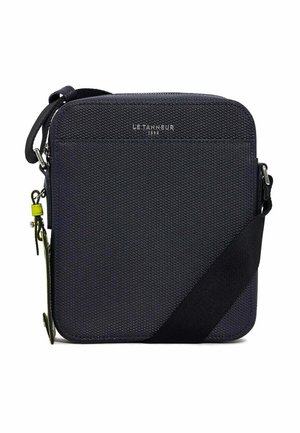 Sac bandoulière synthétique marine avec surface texturée, bandoulière réglable et détail de logo en haut. Il dispose d'une fermeture éclair et de quincaillerie d'accent.