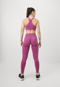 Fitted sportoutfit in gemêleerd magenta, met een racerback sportbeha en high-waisted leggings met contournaden en textuurstof.