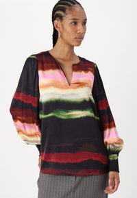 Blusa in satin con profondo scollo a V, maniche lunghe a sbuffo con polsini arricciati e un motivo a strisce astratte multicolori su sfondo nero.