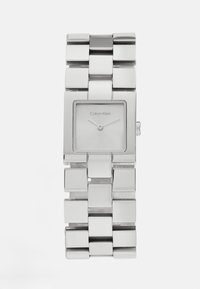 Montre en métal rectangulaire argentée avec un bracelet poli et un cadran minimaliste affichant des aiguilles des heures et des minutes, étiqueté "Calvin Klein".