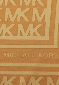 Tkanina z monogramem z pomarańczowym i beżowym wzorem z powtarzającym się logo "MK" oraz tekstem "MICHAEL KORS" o gładkiej powierzchni.