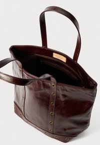 Burgundowa skórzana torba na ramię z dwoma uchwytami, gładka struktura i akcenty w złotym kolorze. Posiada małą wewnętrzną kieszeń na zamek.