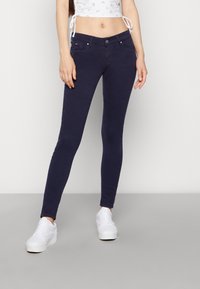 Jeans skinny azul marino fabricados con tejido elástico, que cuentan con cinco bolsillos, cierre frontal con botón y cremallera, y una textura suave.