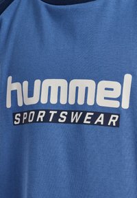 Niebieska bawełniana koszulka z logo "hummel" w białym kolorze oraz napisem "SPORTSWEAR" w granacie, z okrągłym dekoltem i miękką teksturą.
