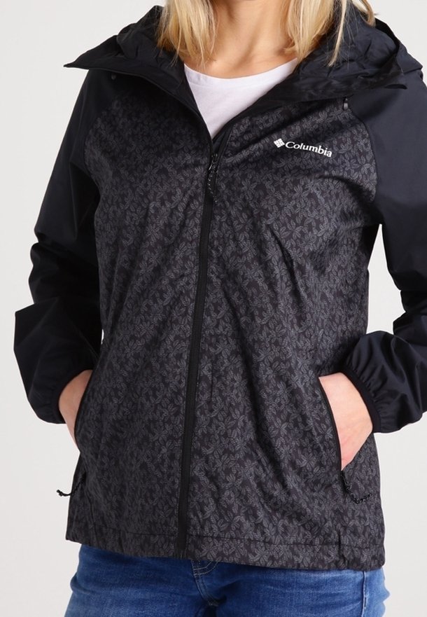 Veste zippée noire et marine avec un motif floral, matière légère, capuche ajustable et poches latérales.