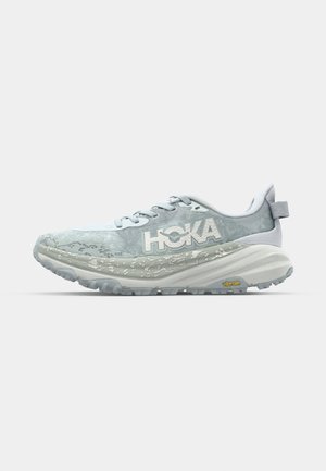 Light blue running shoe with a textured upper, white accents, and a chunky sole. Features HOKA branding and a Vibram outsole for traction.