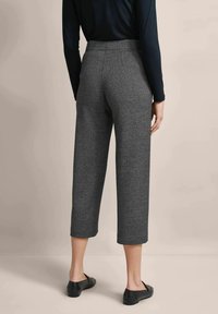 Graue Hahnentrittmuster-Hosen mit glatter Textur, hoher Taille und lässiger Passform, kombiniert mit schwarzen flachen Schuhen. Rückansicht dargestellt.
