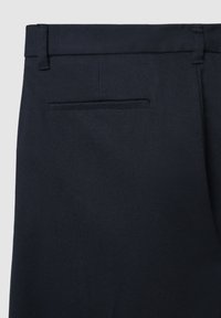 Navyblaue, maßgeschneiderte Hose aus strukturiertem Stoff, mit flacher Vorderseite, Gürtelschlaufen und einer einzelnen Gesäßtasche mit einer dezenten Nähte.