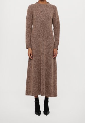 Person wearing a long, brown knit sweater dress with long sleeves, ribbed cuffs and hem, paired with black ankle boots.