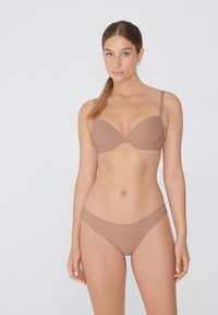 Světlohnědá sada spodního prádla s vycpanou podprsenkou s nastavitelnými ramínky a odpovídající bezešvou bokovou tanga. Hladká textura látky po celém střihu.
