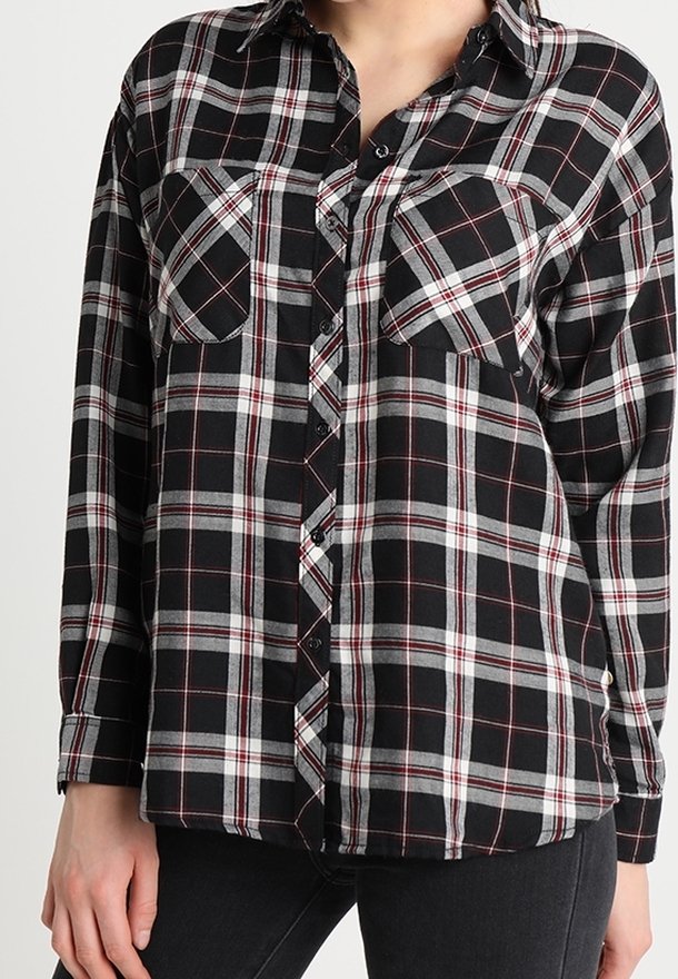 Black, white, and red plaid long-sleeve button-up shirt with two chest pockets worn with black pants.