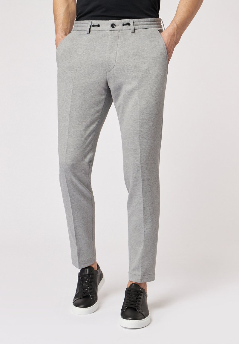 Grijze op maat gemaakte broek met een textuurafwerking, voorzien van een platte voorkant, twee zijzakken en zichtbare riemlussen. Gedirigeerd met zwarte sneakers.