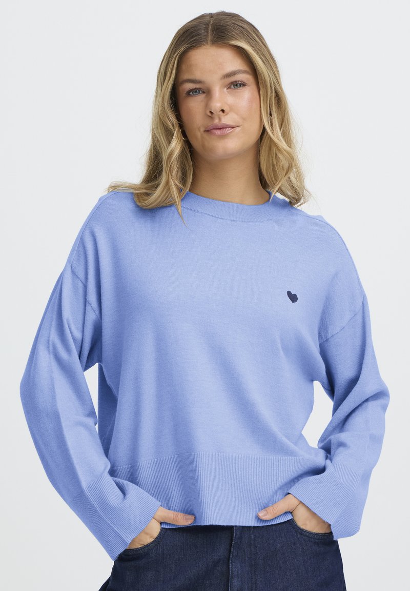 Pull bleu clair à manches longues, ourlet côtelé et petite broderie de cœur foncé sur la poitrine. Tissu doux et coupe décontractée.