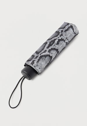 Parapluie compact fermé avec une housse à motif peau de serpent noir et blanc et une sangle de poignet noire sur fond clair.