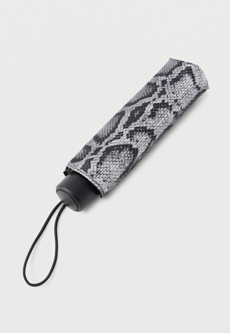 Μικρή κλειστή ομπρέλα με κάλυμμα σε μοτίβο φιδιού σε ασπρόμαυρους τόνους και μαύρο λουράκι καρπού σε ανοιχτό φόντο.