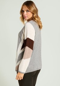 Szary sweter z dzianiny z geometrycznymi kolorowymi rękawami w kremowym, beżowym i brązowym kolorze. Miękka faktura, okrągły dekolt i prążkowane mankiety.