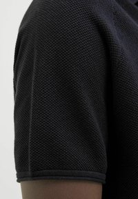 Camisetta nera a maniche corte realizzata in tessuto testurizzato, morbido jersey con colletto a girocollo a coste e finitura pulita all'orlo.