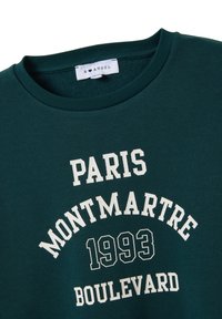 Sudadera verde con cuello redondo, que presenta texto en blanco: "PARÍS", "MONTMARTRE" y "1993 BOULEVARD" en varios estilos de fuente.