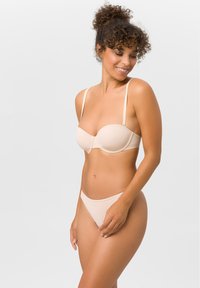 Beiges Unterwäsche-Set mit einem glatten, leicht gepolsterten BH mit verstellbaren Trägern und passendem Tanga. Minimalistisches Design und weicher Stoff.
