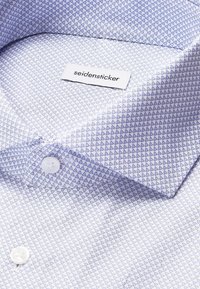 Camicia bianca con un motivo triangolare azzurro chiaro, dotata di colletto con bottoni e bottoni bianchi. L'etichetta riporta "seidensticker".