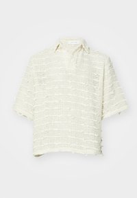 Cămașă cu mâneci scurte, confecționată dintr-un material textil țesut, cu textură, în nuanță albă murdară. Prezintă un guler clasic și margini desfăcute, având o croială lejeră.