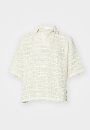 Košile s krátkým rukávem vyrobená z tkané, strukturální látky v odstínu slonové kosti. Má klopový límec a roztrhané okraje s volným střihem.