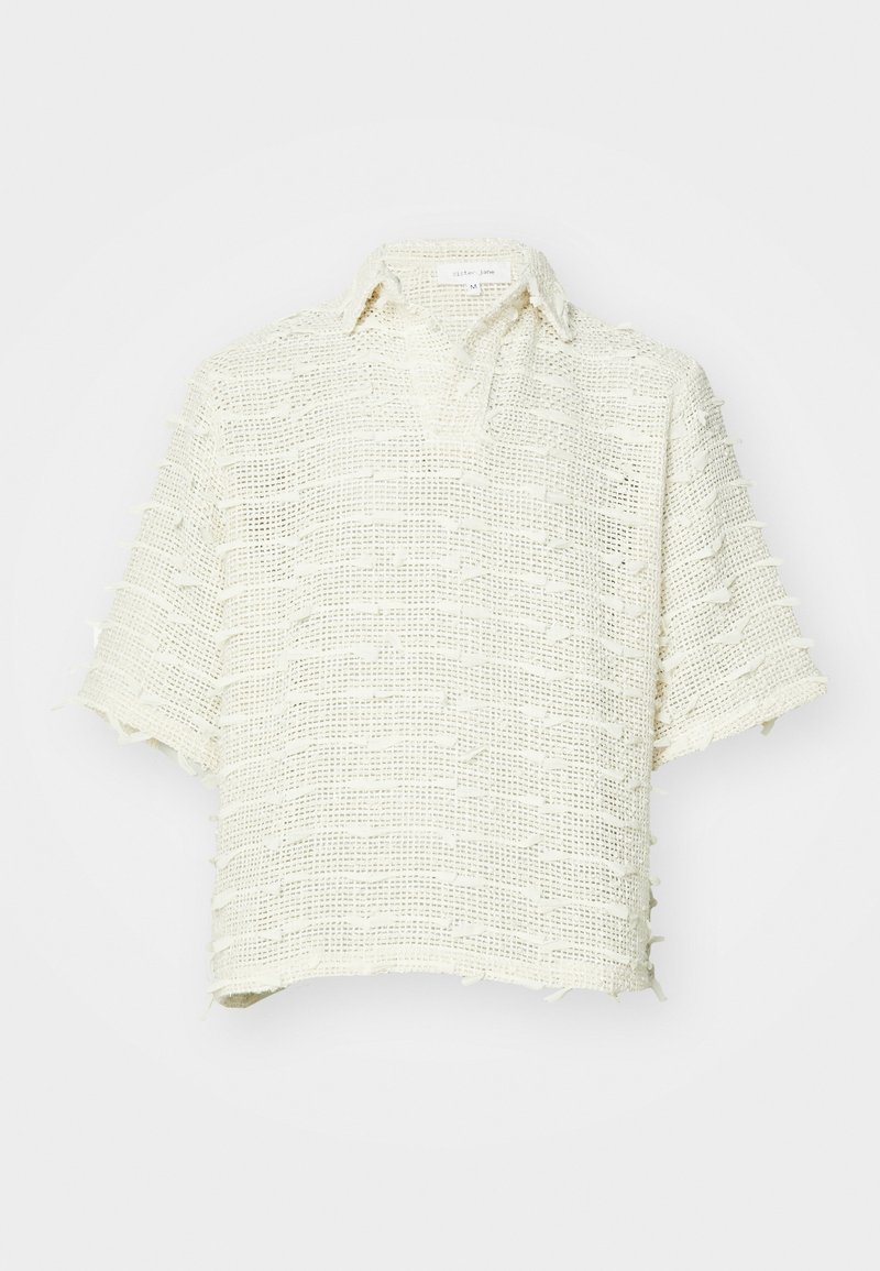 Chemise à manches courtes en tissu tissé et texturé de couleur blanc cassé. Elle présente un col et des bords effilochés avec une coupe décontractée.