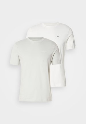 To korteærmede t-shirts i lys grå og hvid. Begge har rund hals og diskret brandlogo på brystet. Blødt bomuldsmateriale.