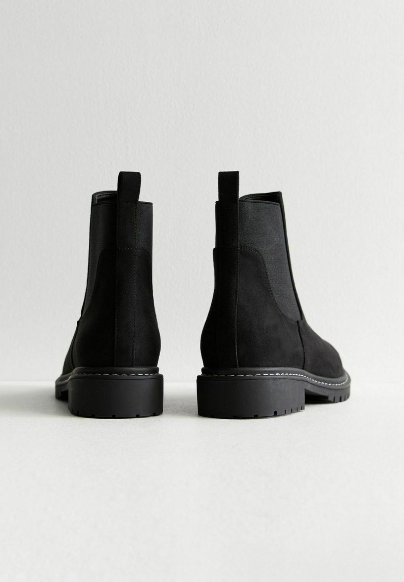 Schwarze Wildleder-Ankle-Boots mit elastischen Seiteneinsätzen und Zugschlaufen, ausgestattet mit einer robusten Gummisohle und dezenten Steppnähten.