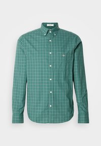 Roheline ruuduline pikkade varrukatega nööpidega särk, millel on krae, valged nupud ja väike logo rinnal. Puuvillane kangas.