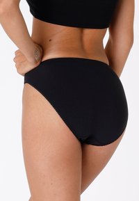 Costume da bagno a vita alta nero con una texture liscia, taglio classico e dettagli di cucitura sottili lungo il bordo superiore.
