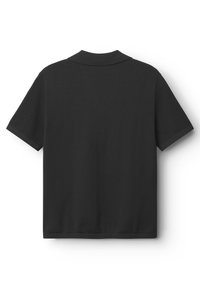 Svart pikétröja med texturerad stickad panel på axlarna, korta ärmar och klassisk krage med rak skärning.