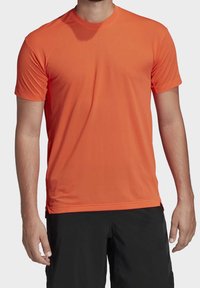 Kortærmet orange atletisk t-shirt lavet af fugttransporterende stof, med rund halsudskæring og glat tekstur.