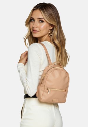 Zaino in nylon beige con forma arrotondata, dettagli in oro, tasca frontale con cerniera e spallacci regolabili. Indossato sulla spalla.