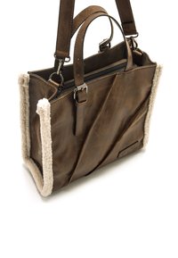 Sac fourre-tout en cuir marron avec surface texturée, doté de garnitures en peluche crème et de deux poignées. Fermeture zippée sur le dessus.