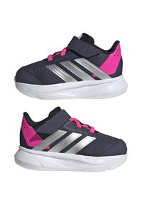 Zapatillas deportivas de malla en color marino con acentos rosas, rayas plateadas y una correa de velcro. Presentan una superficie texturizada y una suela blanca con acolchado.