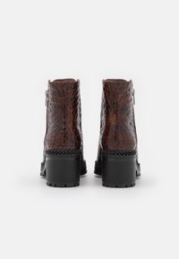 Brown faux crocodile leather ankle boots with a chunky black heel and contrasting stitching on the sole. Side zip closure for easy wear.