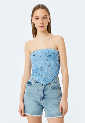 Top blu strapless con motivi paisley e floreali, realizzato in tessuto morbido; abbinato a pantaloni corti in denim a vita alta con orli sfrangiati.