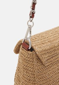 Borsa intrecciata in paglia con una forma strutturata, caratterizzata da un accento in pelle marrone e hardware argentato su una tracolla a catena.