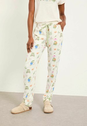 Pantaloni de pijama verde deschis cu un model jucăuș de broaște și flori, talie cu șnur și croială lejeră. Purtați cu saboturi bej.