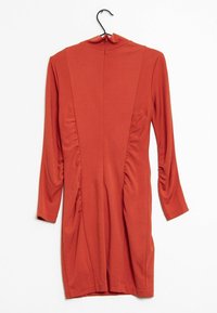 Rdzawopomarańczowa sukienka z długim rękawem, z wysokim kołnierzem, marszczeniem po bokach i gładkim, elastycznym materiałem. Wisi na czarnym haku.