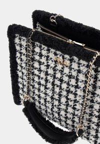 Schwarze und weiße Hahnentrittmuster-Handtasche aus strukturiertem Stoff, mit goldenem Logo, Kettenriemen und samtigen schwarzen Akzenten. Mit Reißverschluss.