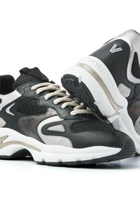 Black and gray sneakers with mesh and leather materials, featuring a patterned accent, thick white sole, and light gray laces.