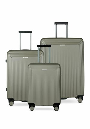 Trois valises rigides de tailles différentes avec des rainures verticales, des poignées télescopiques étendues et quatre roulettes chacune, de couleur grise atténuée.