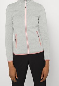 Hellgraue Zip-Jacke mit pinken Akzenten, aus weichem, strukturiertem Material gefertigt, mit zwei Reißverschluss-Taschen und einem hohen Kragen.