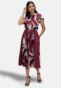 Abito multicolore con motivo floreale in bordeaux e bianco. Maniche corte, vita elastica e tasche laterali. Design lungo fino al pavimento.