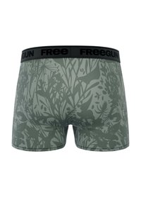 Boxers verts avec un motif de feuilles. La ceinture présente un bandeau noir portant le texte "Freegun", offrant une texture douce.