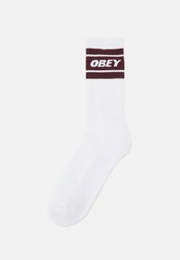 Calcetín de algodón blanco con textura acanalada y una banda color burdeos que presenta la palabra "OBEY" en letras blancas cerca de la parte superior.